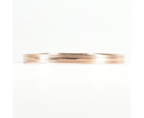 A 9ct rose gold etched design bangle armlet. The bracelet / arm band of circular reverse D form having crosshatched engine tu