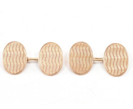 A pair of early 20th Century hallmarked 9ct gold engine turned cufflinks. The cufflinks having oval heads featuring&nbsp; wit