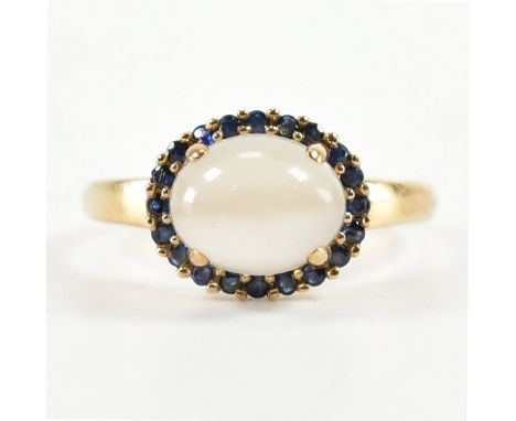 A hallmarked 9ct gold moonstone and sapphire cluster ring. The ring set with an oval cut moonstone cabochon framed by sapphir