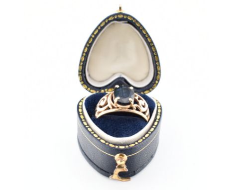 A vintage gold &amp; sapphire single stone ring. The ring having a central oval cut claw set sapphire to pierced scrolling sh