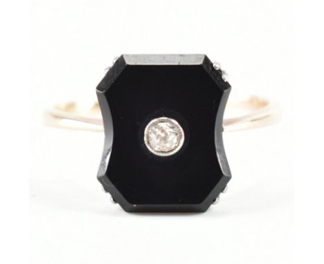 An 18ct gold Art Deco onyx and diamond panel ring. The ring set with a fancy cut plaque having central bezel set old cut diam