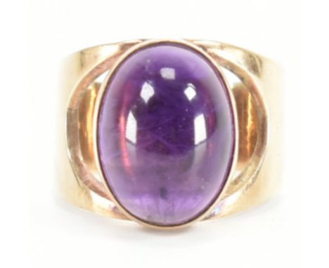 A hallmarked 1960s 9ct gold and amethyst rin. The ring set with a central oval cut amethyst having cut-out shoulders to plain