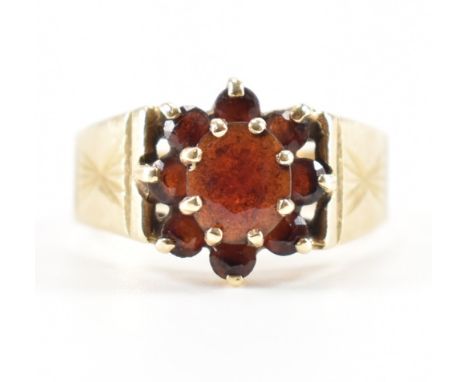 A hallmarked 9ct gold and garnet cluster ring. The ring set with an oval cut garnet with a halo of round cut garnets surround