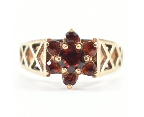 A hallmarked 9ct gold and garnet cluster ring. The ring being set with round cut garnets with pierced lattice work shoulders.