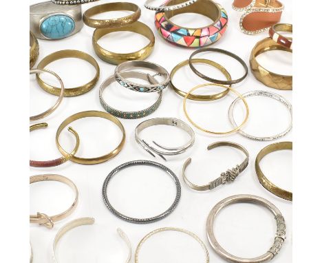 An assorted collection of bangle bracelets. The lot to include; silver, gold &amp; brass tone metals, white stones, simulated