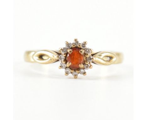 A hallmarked 9ct gold fire opal and diamond ring. The ring being set with an oval cut fire opal with a halo of diamonds. Hall