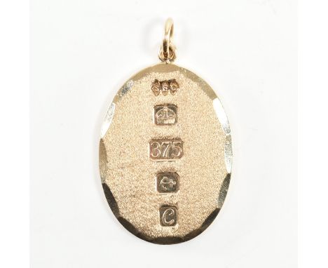 A hallmarked 9ct yellow gold ingot necklace pendant. The pendant of oval form with scalloped facets to the border &amp; textu