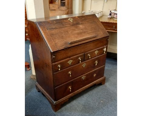 A George III oak bureau with fall front enclosing fitted interior of small drawers, pigeon holes and well above two short and