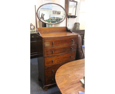 An Edwardian mahogany bow front dressing chest with chequered banding, oval adjustable mirror above five graduated drawers wi