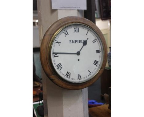 A circular oak wall clock with white dial and Roman numerals marked Enfield 40cm