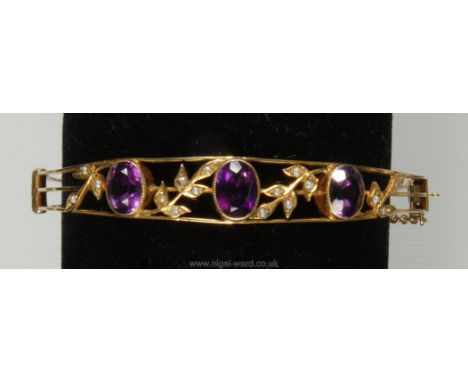 A pretty 9ct gold open work Bangle set with amethysts and seed pearls. 