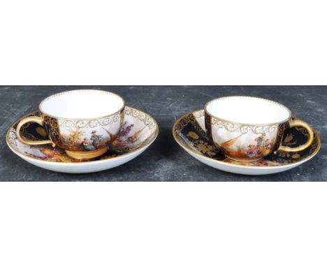 A pair of 19th century Meissen cups and saucers. Cobalt blue and gilt decoration with scenes of lovers and merchants in vigne