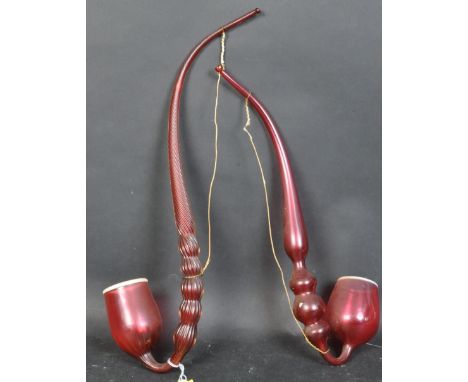 Two Victorian 19th century Nailsea ornamental twisted glass pipe in a cranberry colour with white rims. Largest measures appr