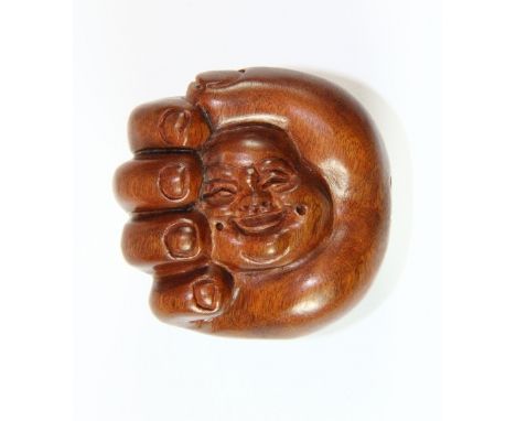 A carved hardwood netsuke of a hand enclosing the Buddha's head, Dia 5.5cm