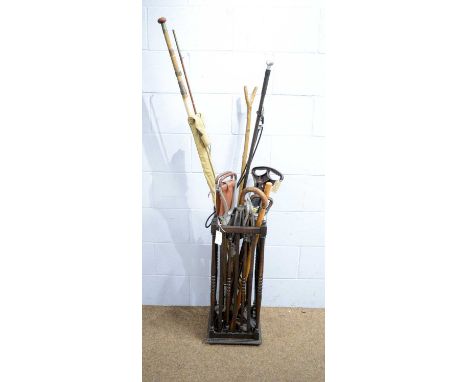 An oak stick stand with spindle and bar sides, with turned finials; and contents, comprising: six shooting sticks, three walk