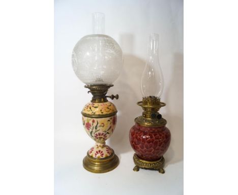 A Victorian F.S. & Co Duplex oil lamp, the red glazed earthenware reservoir within brass mounts and lions' paw feet, with fun