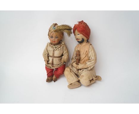 Two Indian dolls, one a cloth example of a turbaned man, kneeling while playing an instrument, 24cm high