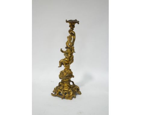 A 19th century French ormolu candlestick with a putti surrounded by C scrolls and flower garlands, on a rococo pierced base, 