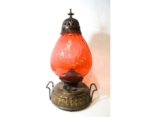 A two handled oil lamp with cranberry tinted glass shade and embossed round brass effect reservoir, overall 64cm high