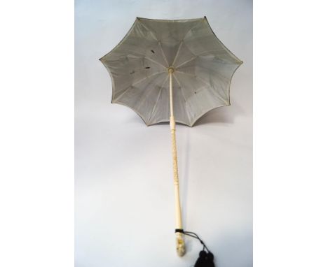 A 1920's Chinese ivory and black silk parasol, the folding handle intricately carved with figures and buildings, terminating 