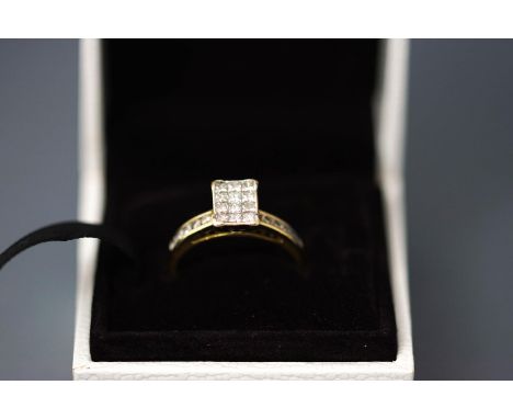 An 18 carat gold diamond ring, the rectangular head set with twelve Princess cut stones, and with five channel set brilliant 