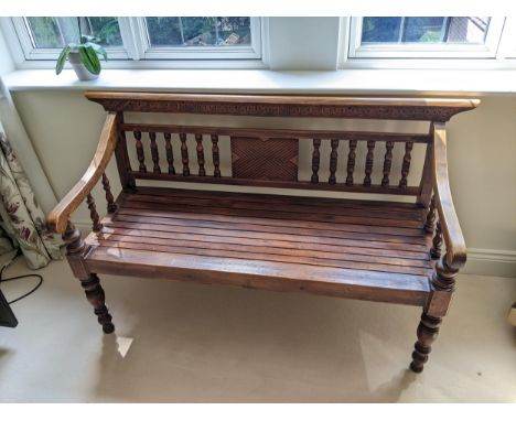 A Thai stained softwood bench with a carved and spindle back and slatted seat on turned legs, 128cm wideLocation: G 