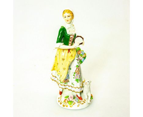 German porcelain; shepherdess playing tambourine with lamb laying by her feet. Green and white coloration; intricate floral d