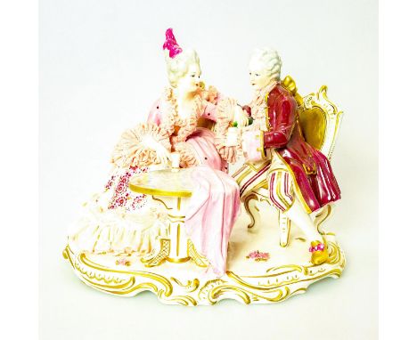 Glossy porcelain figurine with pink porcelain lace accents. A lady and gentleman share a drink. Gold gilt accents on an oval 