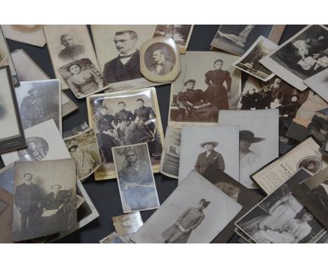 A group of unframed early 20th century sepia and black and white portrait photographs.