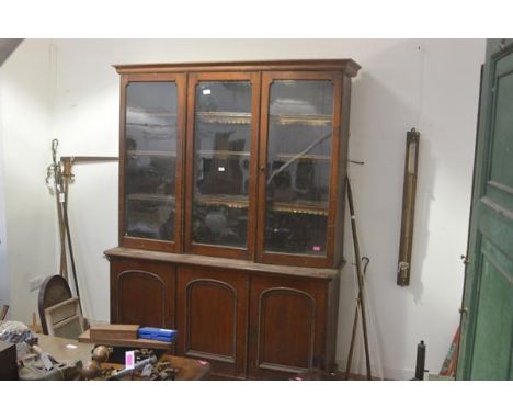 A mid-Victorian oak bookcase cabinet, the moulded cornice over three glazed doors enclosing leather-trimmed shelves, the base