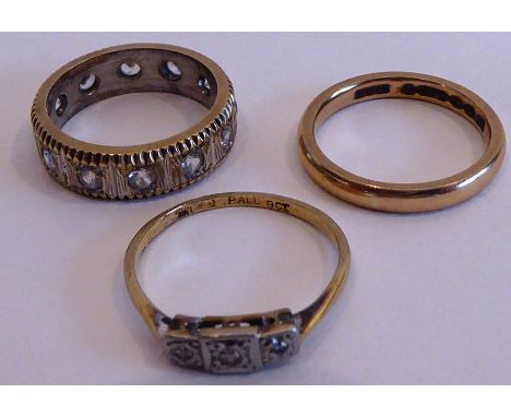 Three rings to include a 9-carat gold eternity ring set with white stones, one further similarly sized 9-carat yellow-gold we