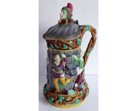 A 19th century Minton Majolica lidded pottery jug; the hinged scallop-shell-shaped cover surmounted with a finial of a jester