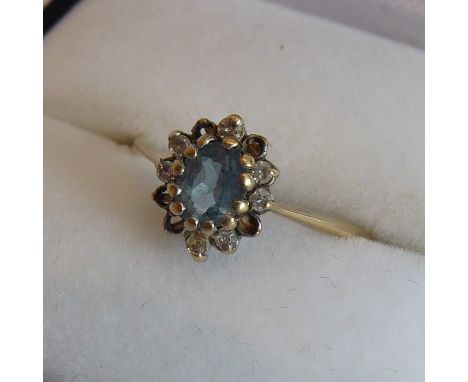 A lady's 9-carat yellow-gold dress ring centrally set with an oval aquamarine surrounded by further smaller white stones (fiv