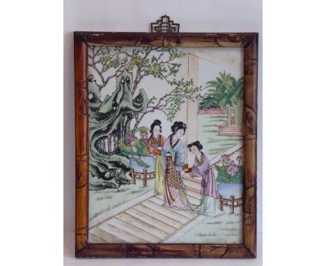 A faux bamboo-framed Chinese porcelain plaque, hand decorated in famille verte enamels depicting a high-ranking female togeth