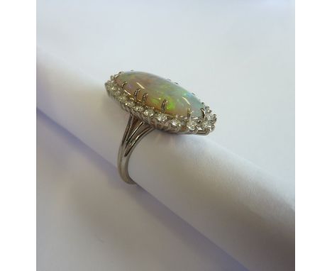 A large and fine opal cluster ring centrally set with a large oval cabouchon opal (23mm long) and surrounded by nice quality 