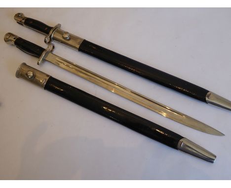 A pair of early-20th century (dated 1907) ceremonial steel bayonets in scabbards, each blade with various marks including Wil