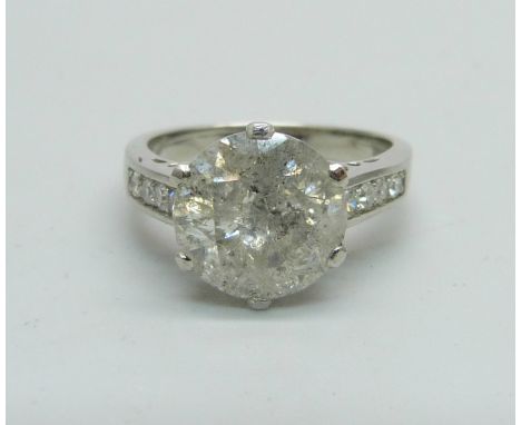 A hallmarked platinum solitaire diamond ring with diamond set shoulders, 3.80cts, 6.1g, M 