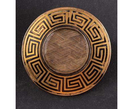 A Victorian mourning brooch, the central glazed compartment with hairwork, bordered by black enamel Greek key pattern, inscri