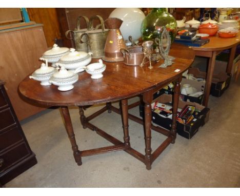 An oak gate leg dining table raised on turned supports
