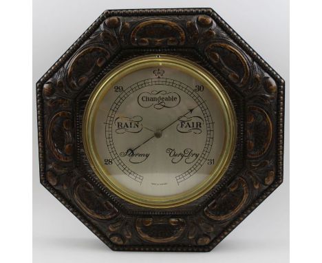 A mid 20th carved oak cased wall barometer, silvered dial, glazed within a brass bezel, the dial 19cm, overall 36cm octagonal