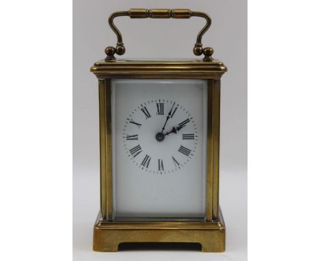 A late 19th century brass carriage clock, hinged bale handle, white enamel dial with Roman Numerals, the case 11cm high, with