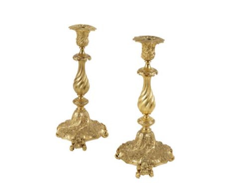 A PAIR OF 19TH CENTURY GILT METAL CANDLESTICKS with central spiral shafts above spreading tripod feet with all over foliate r