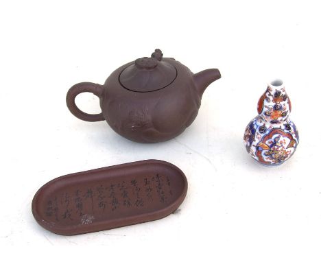 A Chinese Yixing pottery teapot, 6.5cms (2.5ins) high; together with a Yixing pottery dish decorated with calligraphy, 12cms 