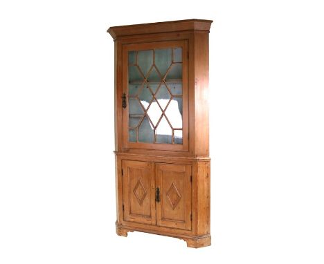 A 19th century stripped pine corner cupboard, the astragal glazed door with shelved interior above a pair of panelled doors, 