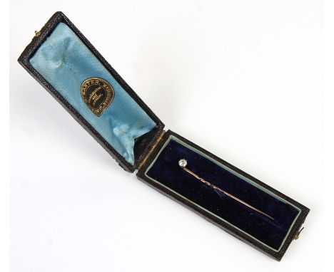 A yellow metal and diamond solitaire stick pin in a 'G Baxter' box.