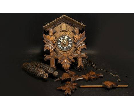 Wooden German Cuckoo Clock of traditional form, with engravings of a bird with leaves and cruciforms.  Cone shaped weights ma