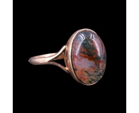 An early 1970s moss agate ring, comprising an oval mineral cabochon (approx 14 mm x 11 mm) bezel set between the bifurcated s