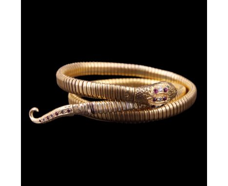 A 1960s 9ct gold serpent bangle, the snake's head and tail set with emeralds, rubies and diamonds, 34 g (steel sprung)
