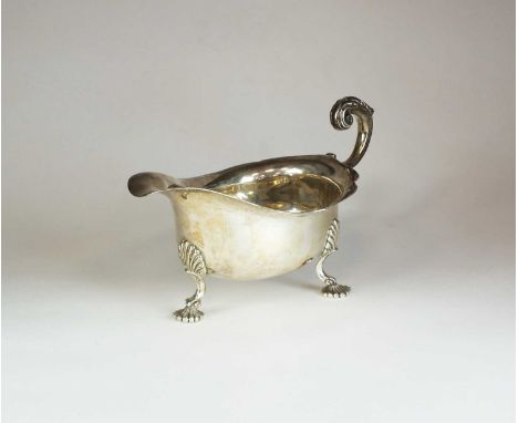 A Harrods silver sauce boat, London 1925, of typical form with cusped rim, acanthus leaf capped scroll handle and raised on t