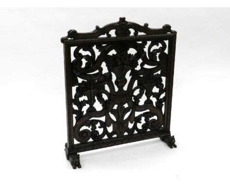 A late 19th century, Renaissance style, pitch pine and oak firescreen, carved and pierced with vases of flowers swags and scr